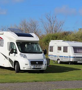Row of motorhomes and travel trailers parked outside for exterior repair