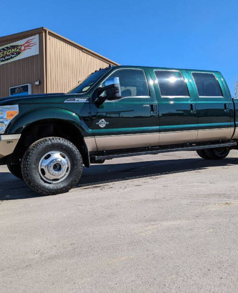 Green and tan six-door Ford dually parked outside the Kustomz shop