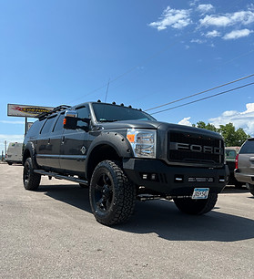 Black lifted six-door Ford Super Duty with aftermarket bumper and wheels