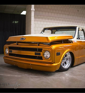 Lowered orange and white Chevrolet C10 pickup with polished wheels on a show floor